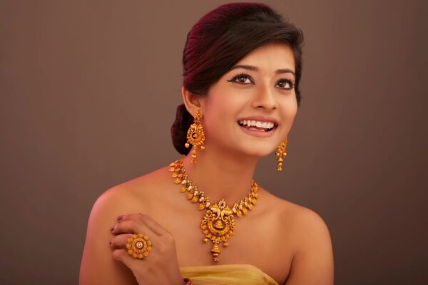 A woman wearing gold jewelry and earrings.