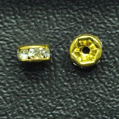 A pair of gold colored beads sitting on top of a black surface.