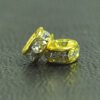 A pair of gold colored metal beads with clear rhinestones.