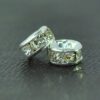 A pair of silver colored metal beads with clear rhinestones.
