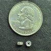 A coin and some small metal parts on top of a table.
