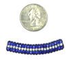 A close up of a coin next to a bead
