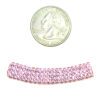 A pink bead is sitting next to a coin.