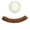 A small amount of orange beads are next to a penny for scale.