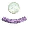 A coin and some purple beads next to each other