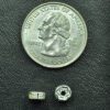 A coin and some small beads on top of a table.