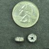 A coin and some silver beads on a table