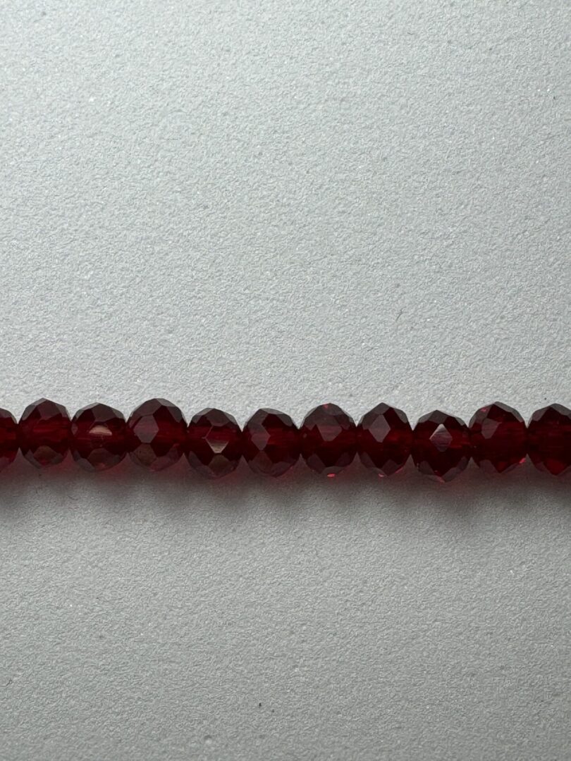 Row of red faceted glass beads.