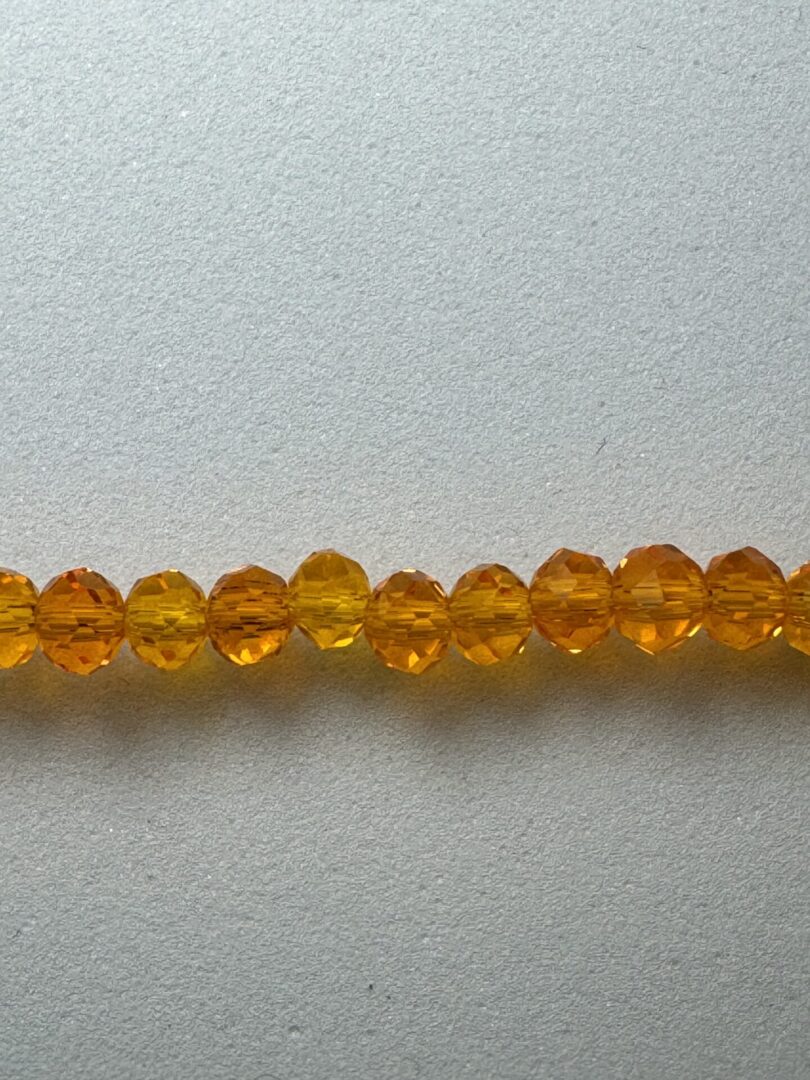 Row of orange faceted glass beads.