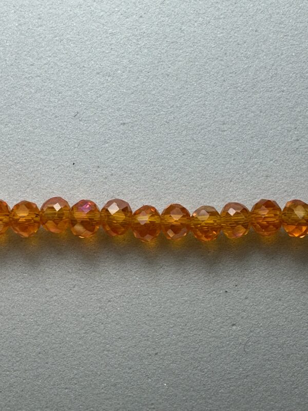 Row of amber glass beads on grey background.