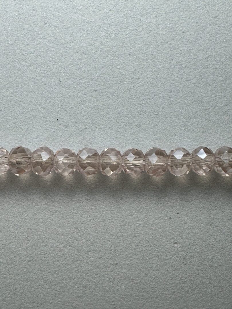 Row of light pink faceted glass beads.