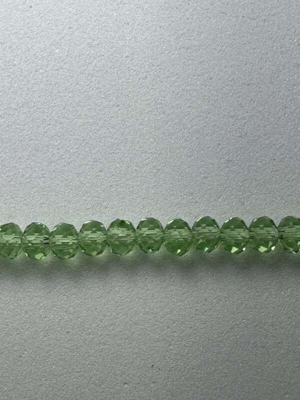 Green faceted glass beads on white background.