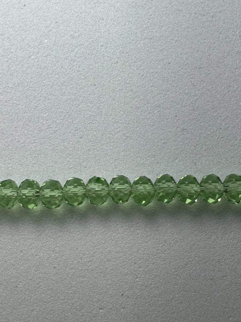 Green faceted glass beads on white background.