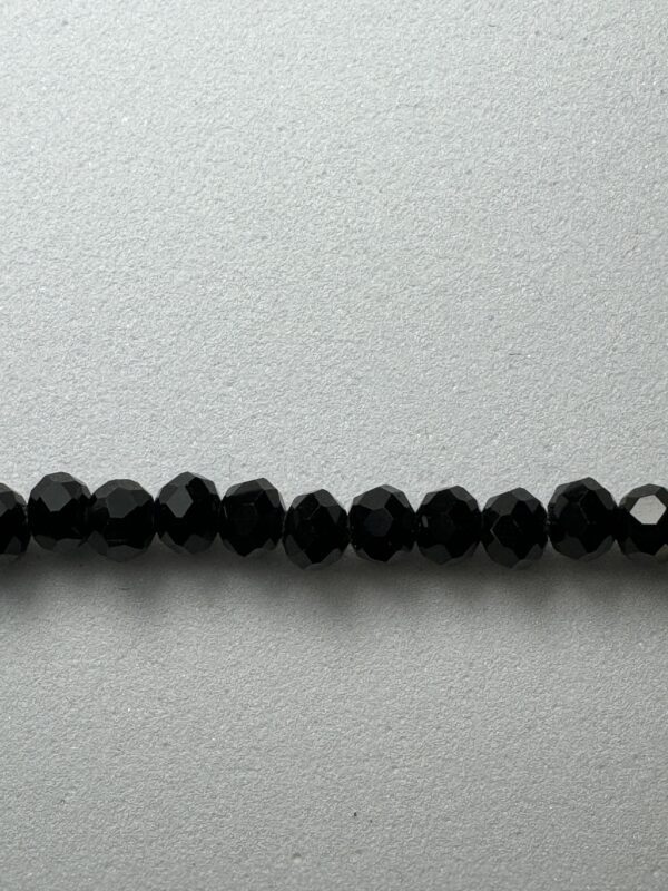 Black faceted beads on white background.