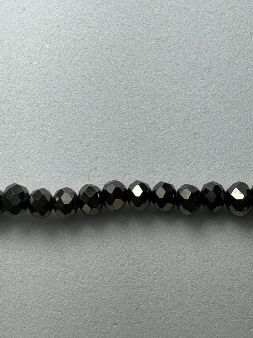 Black faceted beads on a grey background.