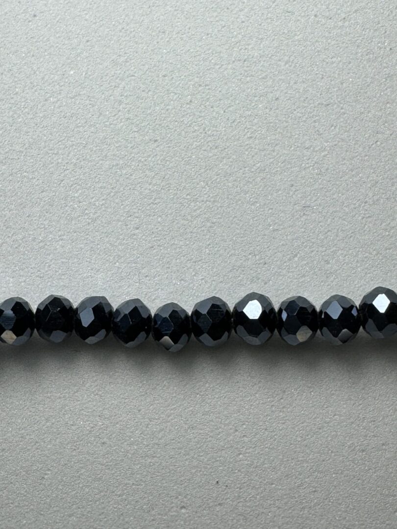 Row of black faceted beads on gray background.