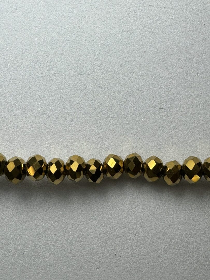 Row of gold faceted beads on white background.