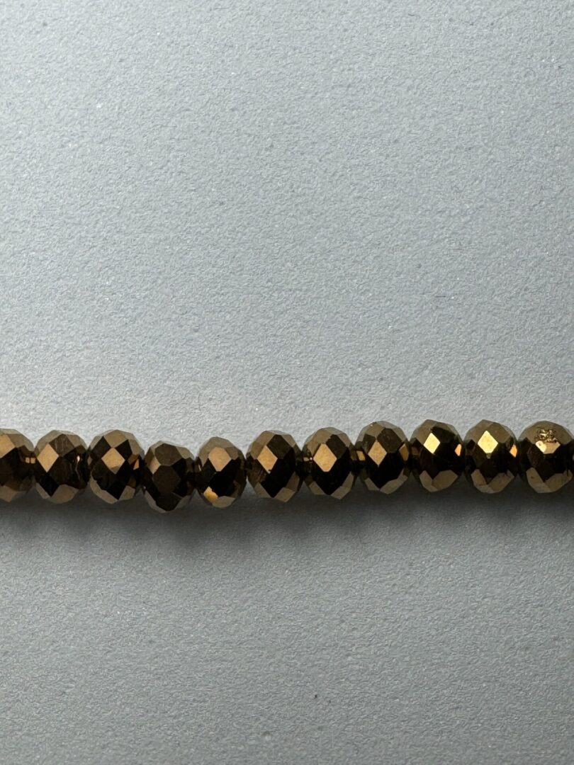 Row of shiny bronze beads on a white background.