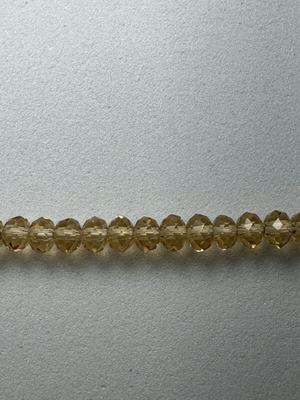 Row of amber glass beads on gray surface.