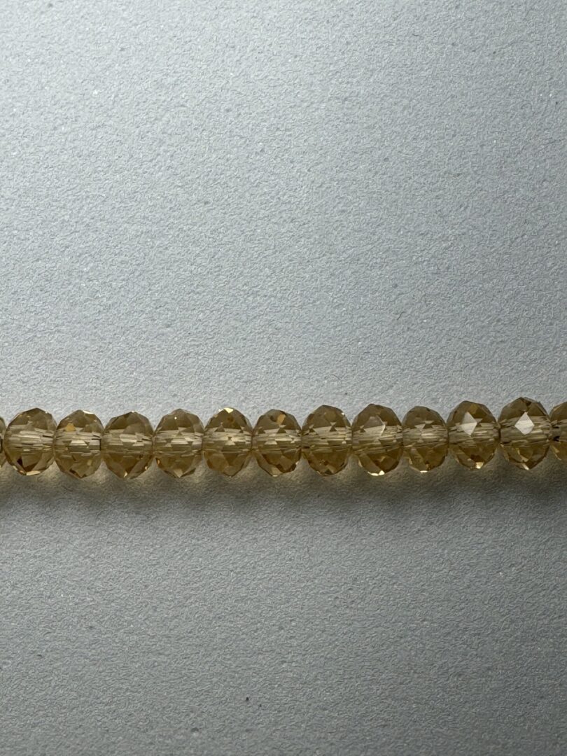 Row of amber glass beads on gray surface.