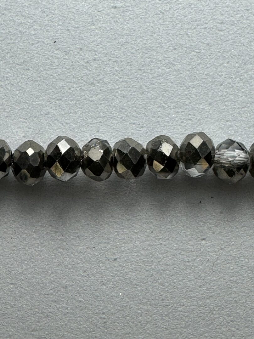 Black faceted glass beads on gray background.