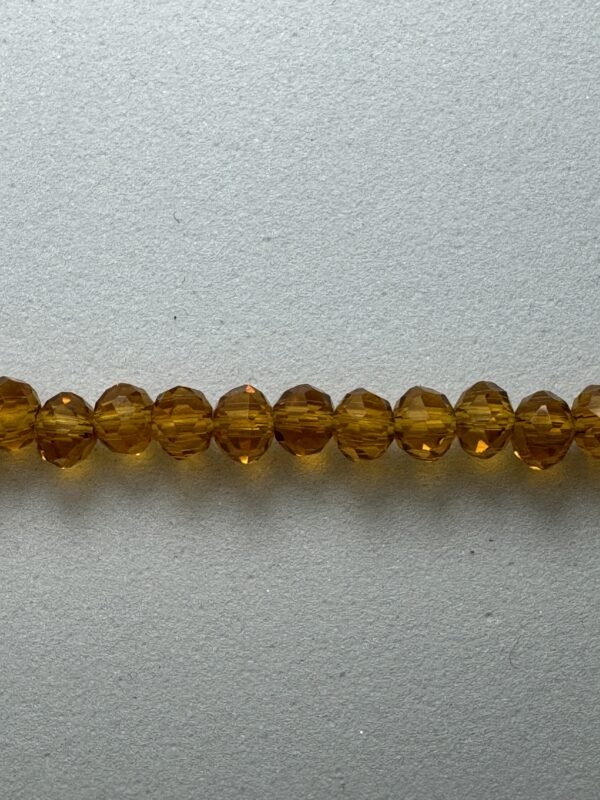 Row of amber glass beads on white.