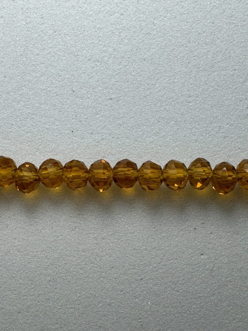 Row of amber glass beads on white.