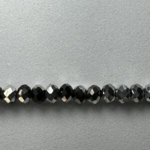 Row of black faceted beads on white background.