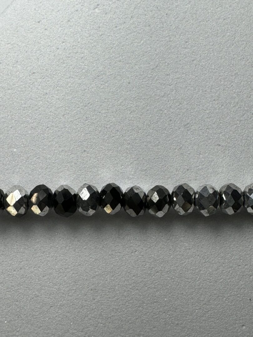 Row of black faceted beads on white background.