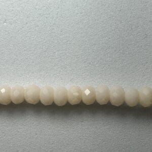 Row of white faceted beads on gray background.