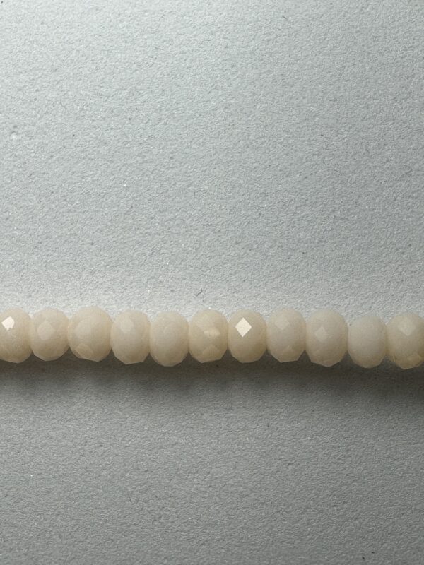 Row of white faceted beads on gray background.