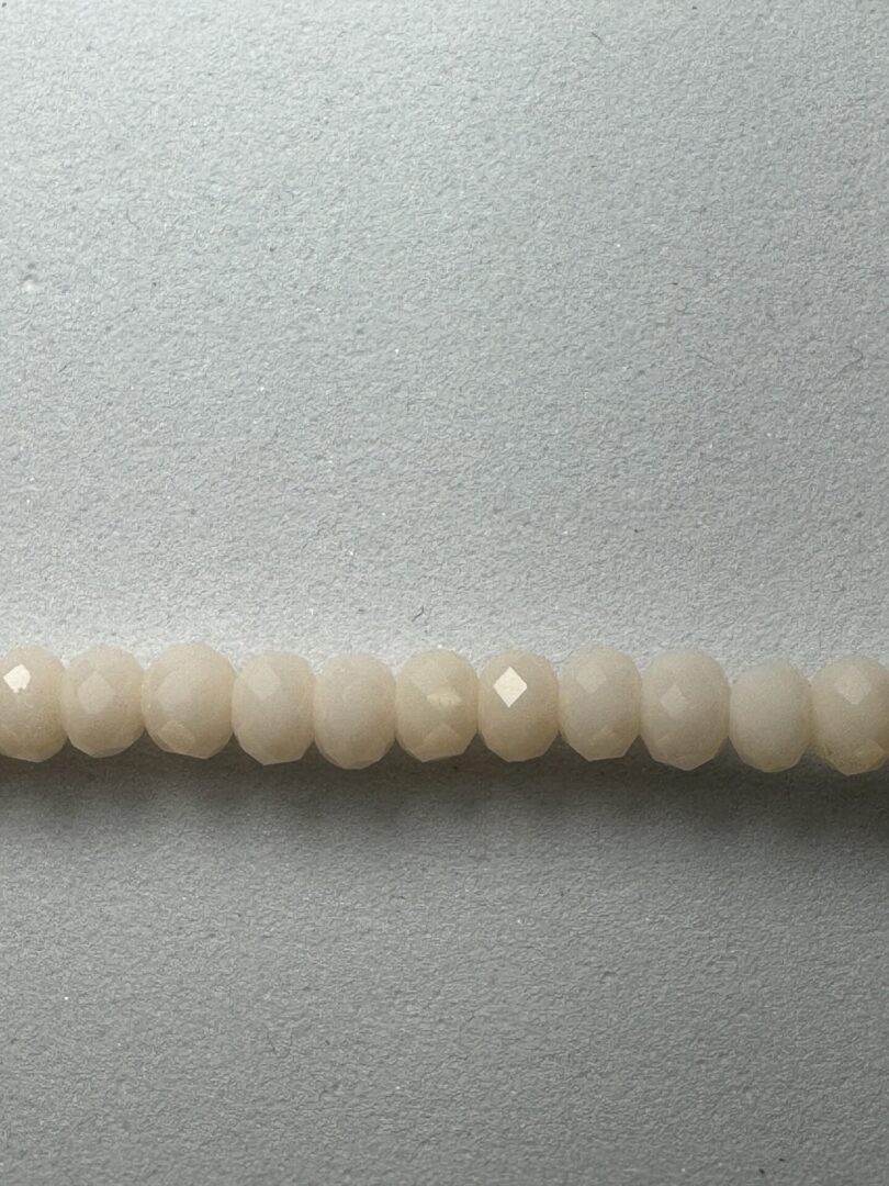 Row of white faceted beads on gray background.