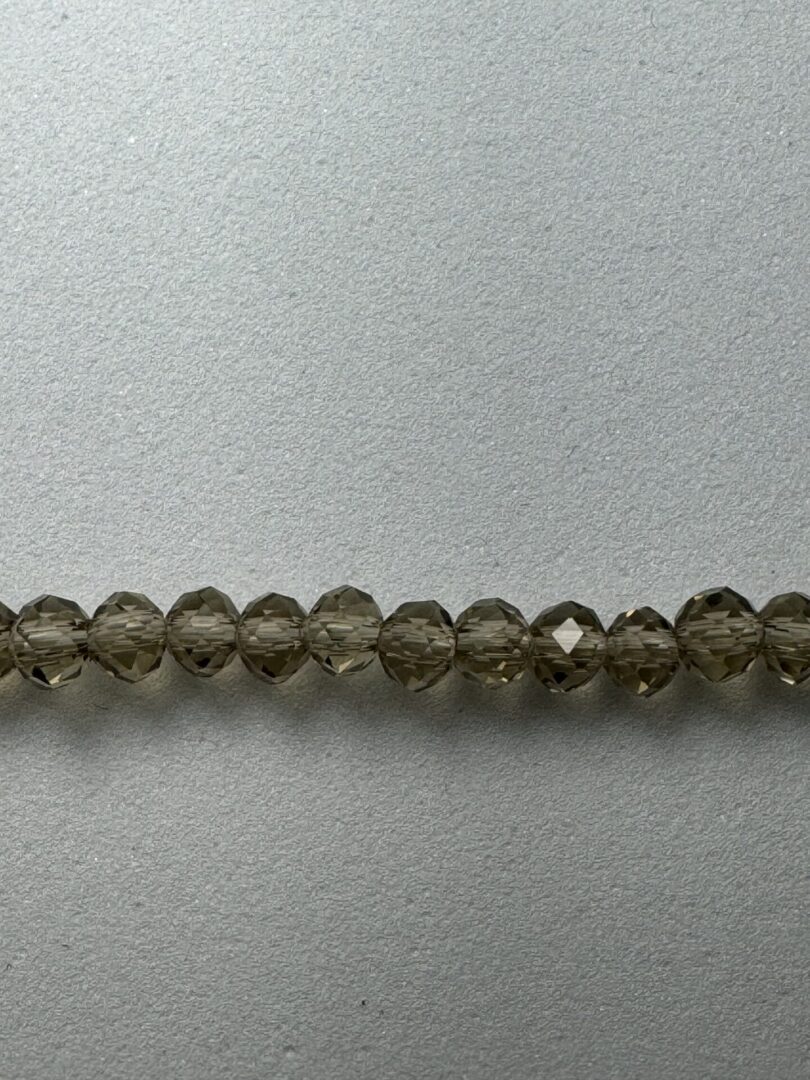 Row of smoky quartz beads on grey surface.