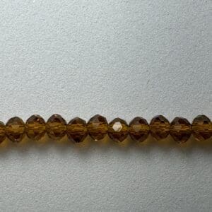 Row of amber glass beads on a gray background.