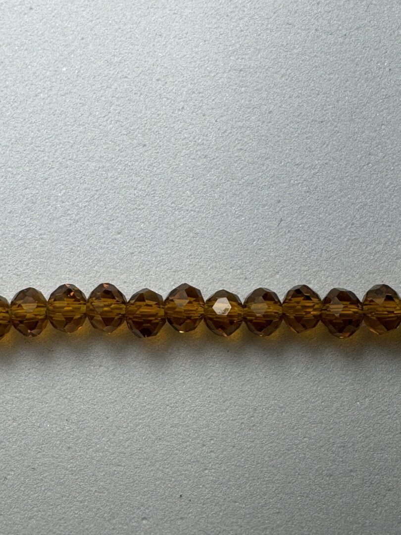 Row of amber glass beads on a gray background.