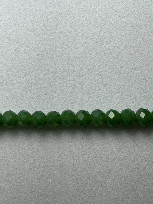 Row of green faceted beads on white.