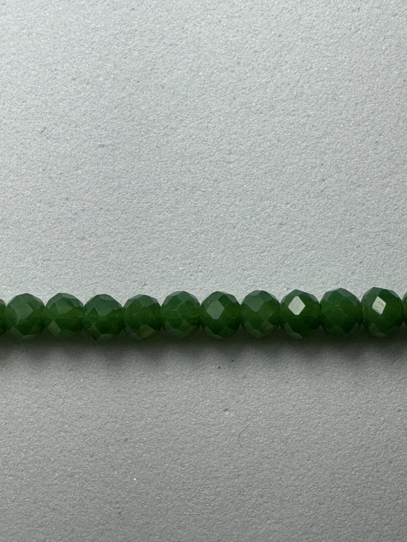 Row of green faceted beads on white.