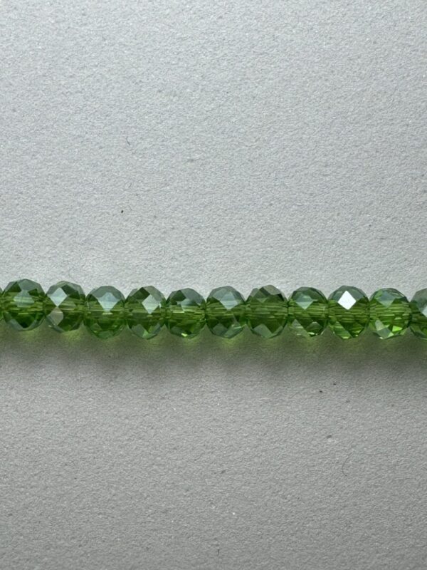 Green faceted glass beads on white background.