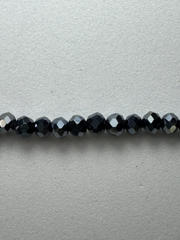 Black faceted glass beads on a grey background.