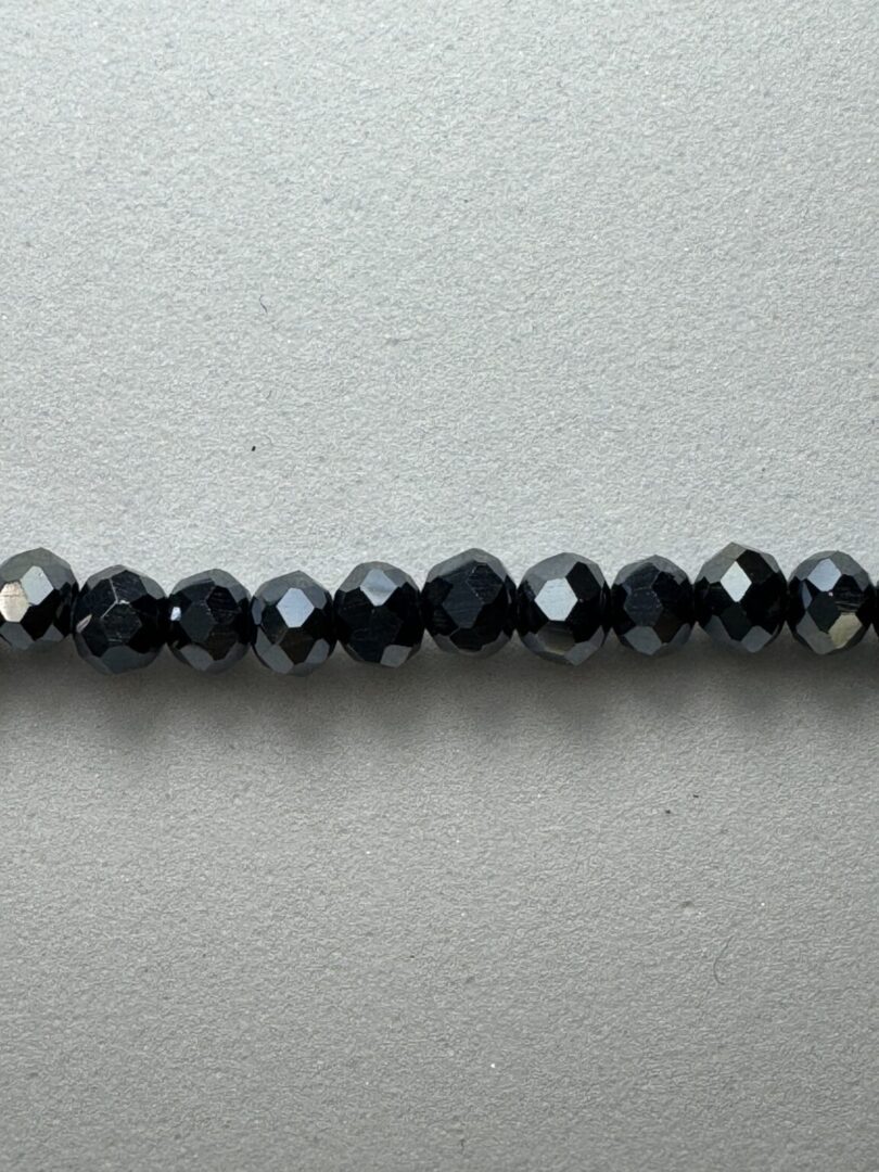 Black faceted glass beads on a grey background.