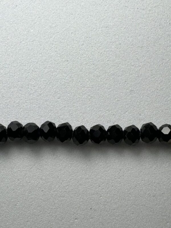 Black faceted beads on a white surface.