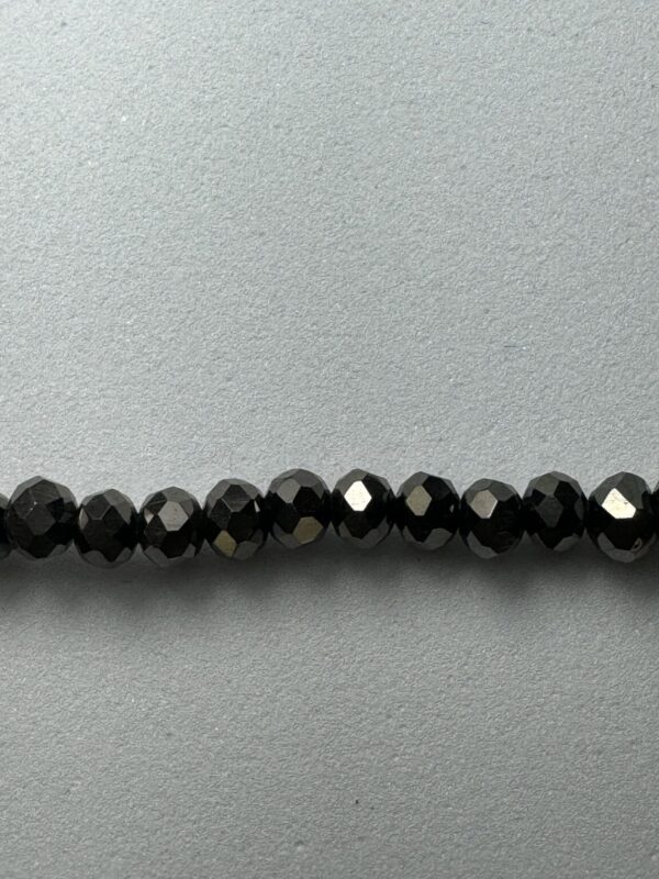 Row of black faceted beads on gray background.