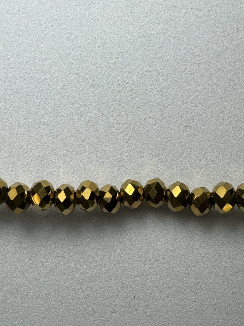 Gold faceted beads on white background.