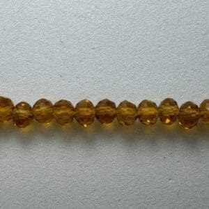 Row of amber glass beads on gray background.