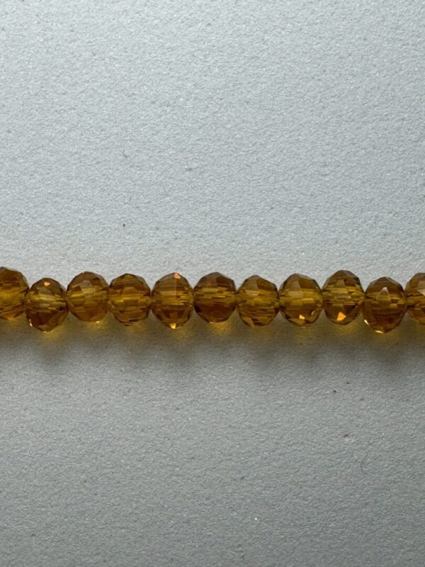 Row of amber glass beads on gray background.