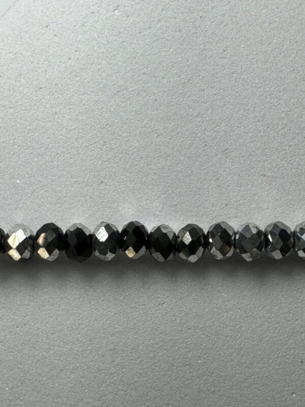 Row of black faceted gemstone beads.