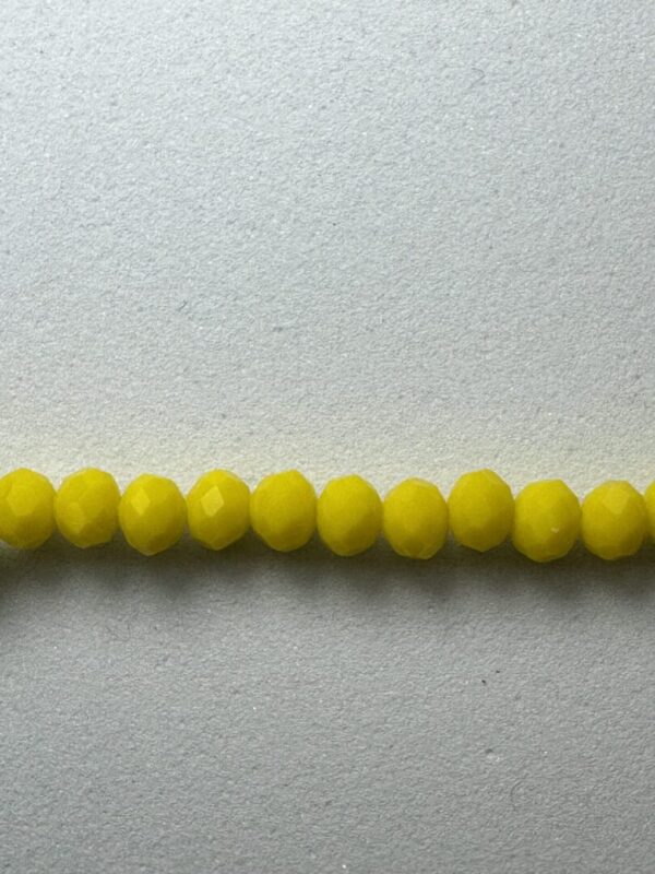 Row of yellow faceted beads on white background.