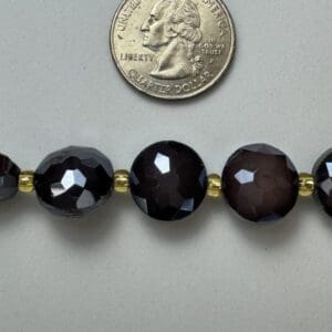 Black faceted beads with gold spacers.