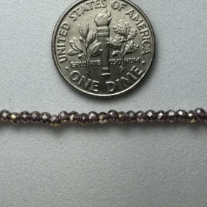 Dime next to dark glass beads.