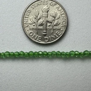 Green glass beads next to dime.